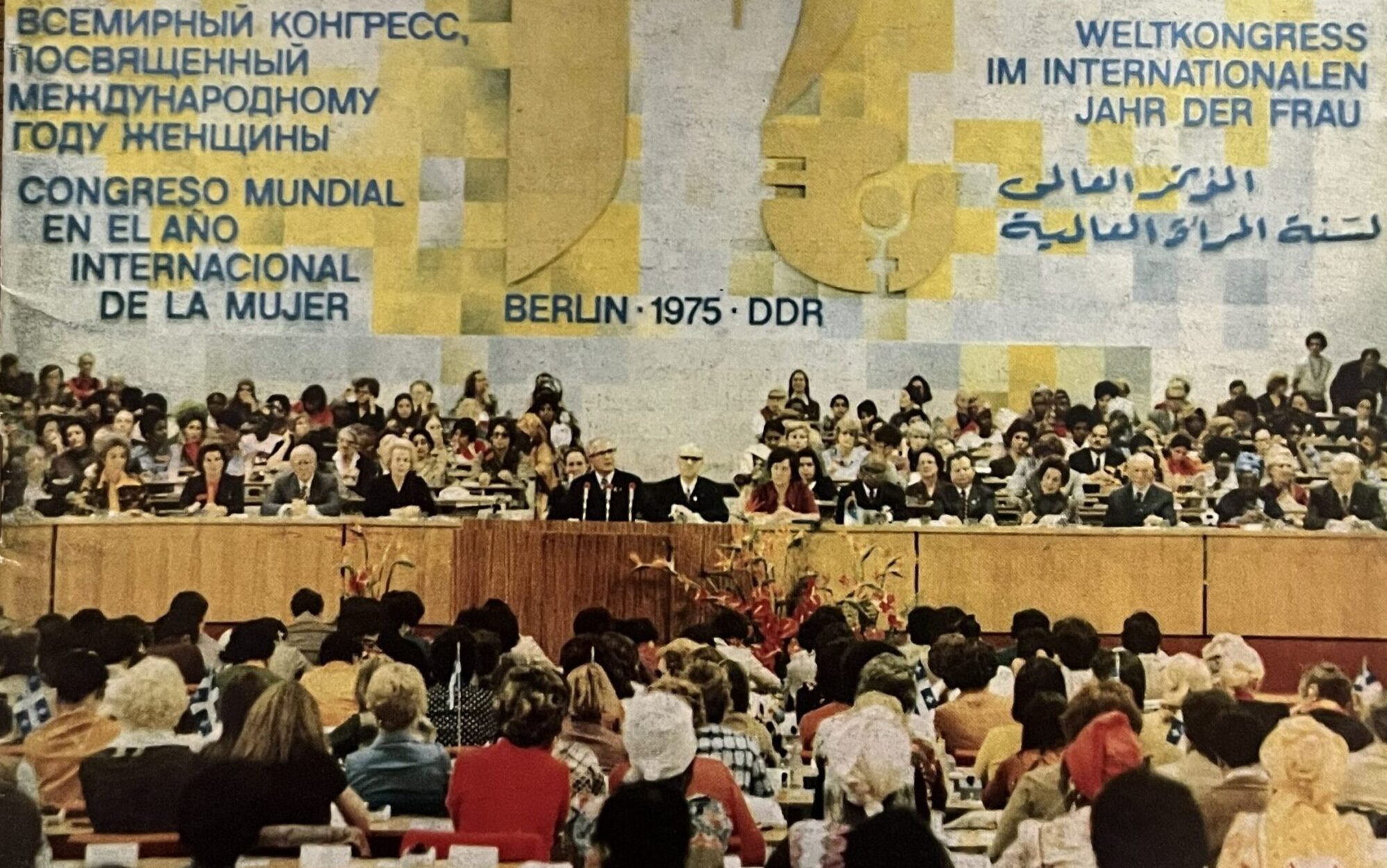 A magazine front cover showing a large gathering of seated women listening to a speaker. A title reads Berlin - 1975 - DDR.