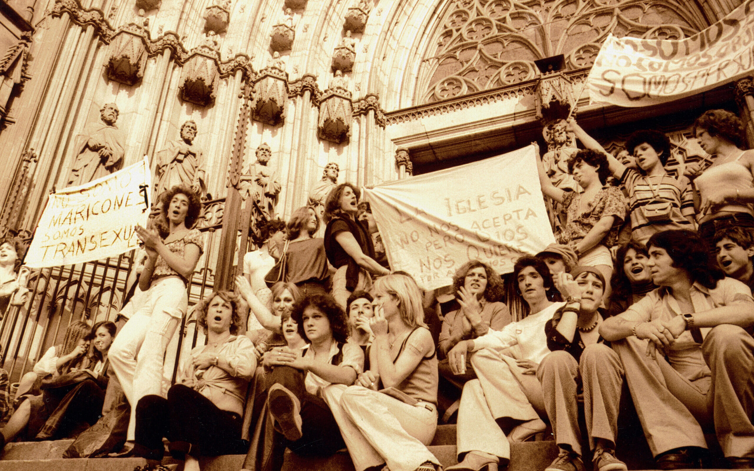 a sepia photograph showing a group of young people holding banners and sitting and standing on the steps of a cathedral.